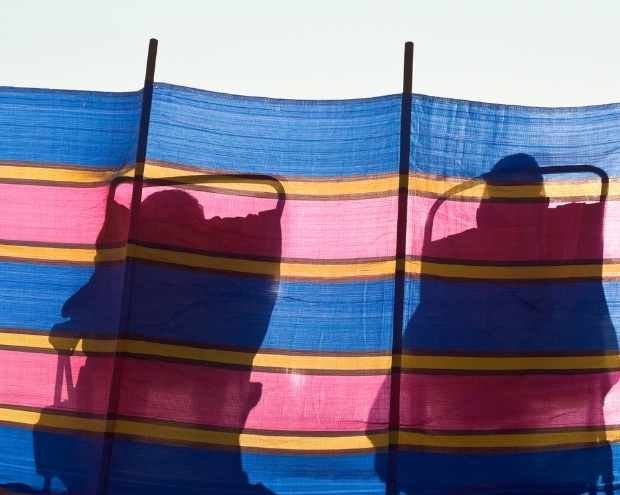 a couple in shadow against a wind break