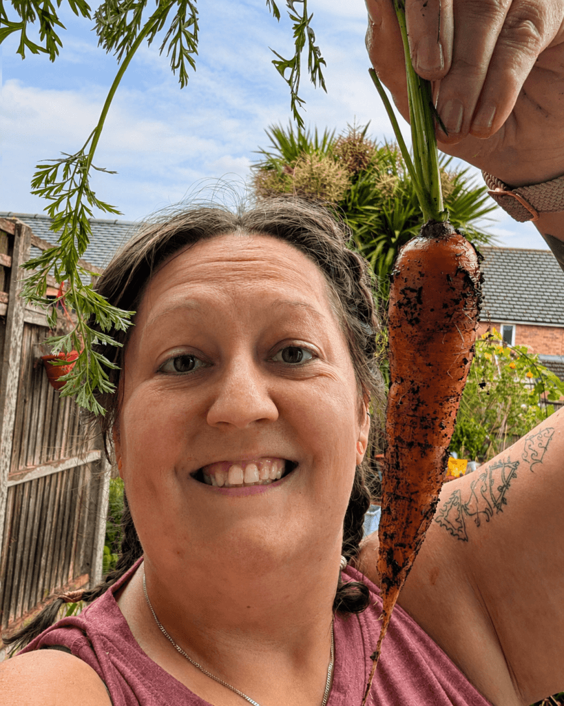Niki smiling with a freshly harvested carrot